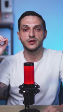 Kendine güvenen dövmeli adam modern bir stüdyoda podcast yaparken düşüncelerini paylaşıyor. Temiz görüntüler, yumuşak ışıklandırma ve gevşek vücut dili..