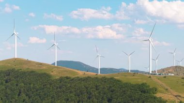 Shipka yakınlarındaki bir dağ sırtı boyunca dönen çoklu rüzgar türbinlerinin geniş drone görüntüsü. Doğal arazi ve hava koşullarıyla uyum içinde yenilenebilir enerji. 