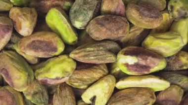 Canlı yeşil renklerini ve doğal dokularını gösteren ham kabuklu fıstıklı çekirdeklerin detaylı bir makro görüntüsü.