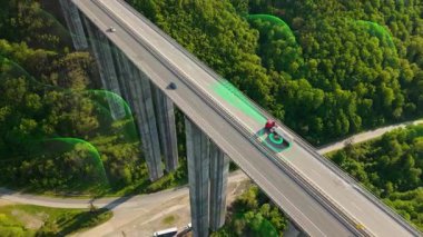 cinematic aerial view of a futuristic self-driving truck with cargo trailer navigating a scenic viaduct road. This driverless semi combines AI control, machine learning, GPS tracking, and renewable