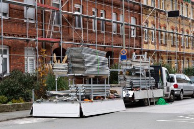 Çelik, yapı iskelesi gibi inşaat araçları, tadilat çalışmaları için araba üzerinde hazırlanıyor. Bina iskele ile çevrili..