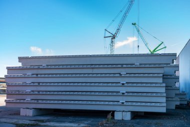 İnşaat alanlarına beton döşemeler yığılmış. Arka planda kule vinçleri.