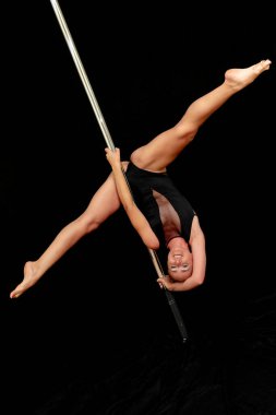 Siyah arka planda genç ve güzel bir direk dansçısı..