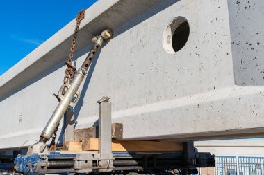 Hidrolik mekanizma ve zincirlerle bir araba platformuna bağlanmış büyük bir beton kiriş. Yakın plan..