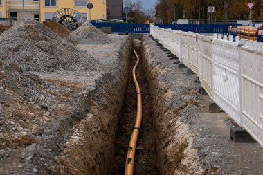 İnşaat alanında turuncu plastik borulu bir siper vardı. Beyaz ve mavi plastik bariyerlerden yapılmış eskrim.