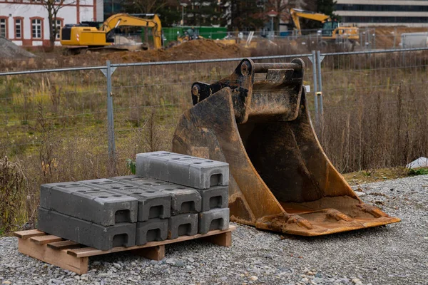 Concrete blocks and bulldozer bucket at construction site. Close-up.