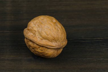 Single walnut on a dark brown table. Close up.