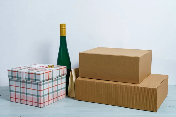 Gift boxes and a bottle of wine on a wooden table on a white background. Close up.