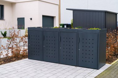 Stylish gray container for trash bins and garbage bins near residential building.