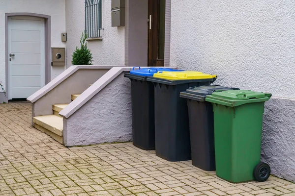 Plastic multicolored trash cans for garbage near the entrance to a residential building.