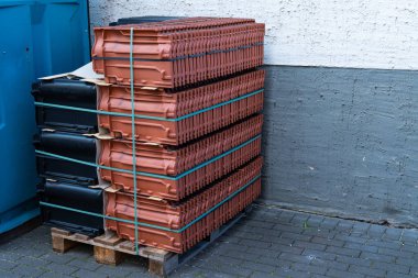 Çatı kiremitleri siyah ve kahverengi terracotta bir palette istiflenmiş. Kapat..