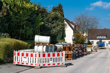 Yolun kenarına dizilmiş beton ve seramik su boruları. Beyaz ve kırmızı plastik mobil çitler.