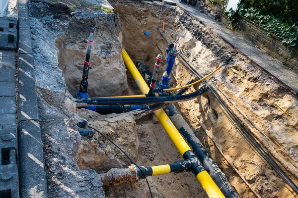 Kazılmış bir siperde sarı, mavi, siyah plastik borular ve kablolar. Yukarıdan görüntüle.