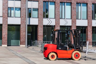 Büyük bir binanın arka planına karşı bir inşaat alanında forklift. Yan görünüm.