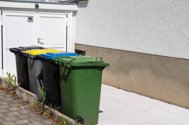 Ayrı atık toplama için çok renkli plastik kutular garajın yanında duruyor..