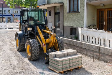 Şehirdeki bir inşaat alanında palet kaplı sarı bir kamyon..