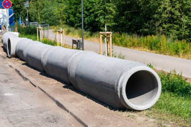 Su tesisatı ve drenaj için gri beton borular inşaat sahasının kenarında duruyor..