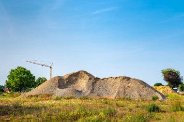 Mavi gökyüzünün altındaki inşaat alanında büyük bir moloz yığını..