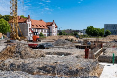 Binanın temelinin inşaatı ile ilgili çalışmalar devam ediyor. Arkaplanda ekipman kaldırılıyor.