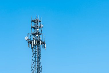 Açık mavi gökyüzüne karşı uydu antenleriyle yayın kulesi 5G.
