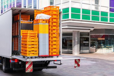 Plastik turuncu ve beyaz kutuları olan bir araba şehrin yaya bölgesinde duruyor..