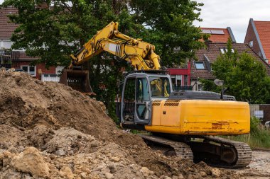 Sarı bir kazıcının bir inşaat alanında yığılı toprak yığınının dikiz görüntüsü.