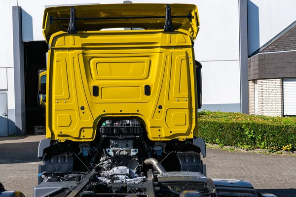 Rear view of the cab of a bright yellow cargo semi-trailer.