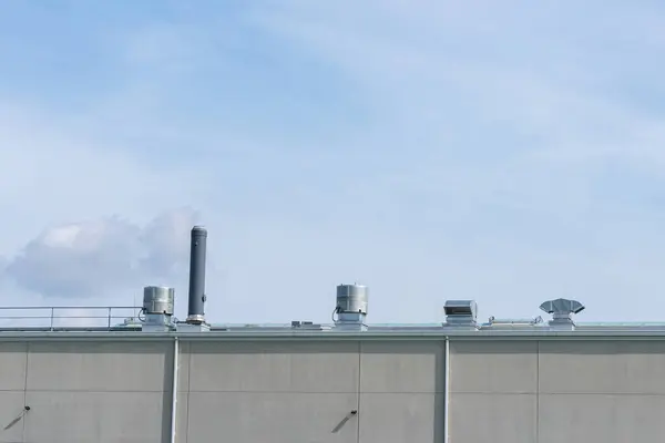 明るい雲の青空の下に金属換気パイプが付いている産業建物の屋根 — ストック写真