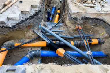 Çok renkli plastik boruları olan kazılmış siperleri olan bir inşaat alanı. Boru hattı geçiyor.