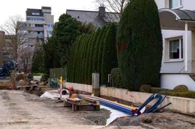 Bir yerleşim bölgesine boru döşemek için inşaat çalışması. Plastik çok renkli borular ve yeşil alanlar.