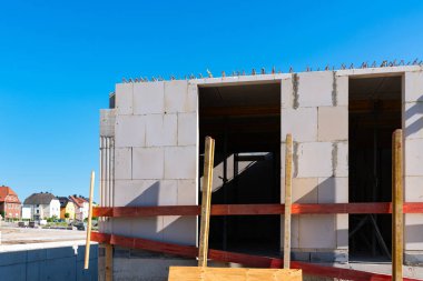 Bitmemiş bir evin duvarının bir kısmı açık mavi gökyüzünün altındaki beton bloklardan inşa ediliyor..