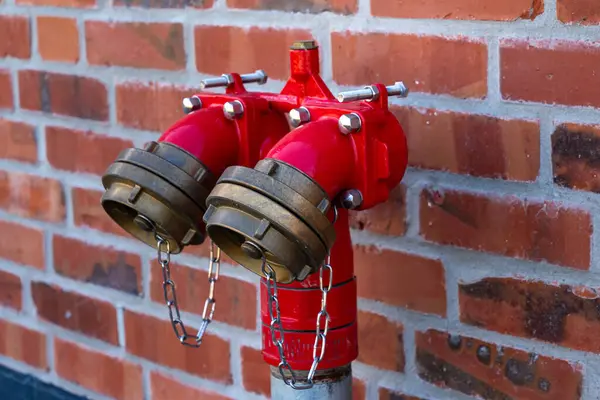 stock image Bright red fire hydrants on a brick wall. Close up.