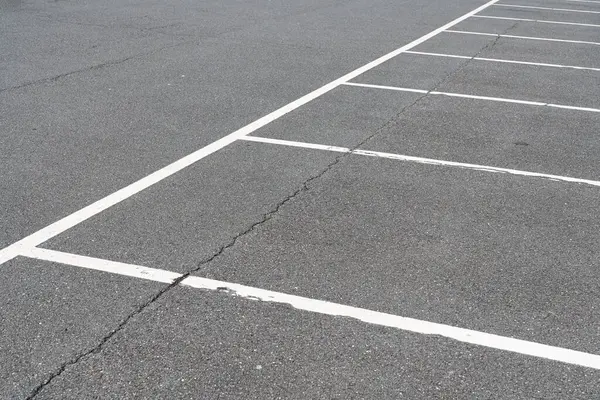 Gri asfalttaki boş otoparkın beyaz işaretleri. Üst görünüm.