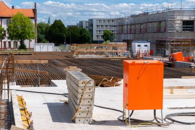 Turuncu elektrik kutusu, demir çubuğu ve betonu olan bir inşaat alanı..