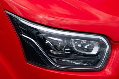 Kırmızı arabaların yakın plan görüntüsü ön far, parlak tasarımı ve modern özellikleri sergileniyor..