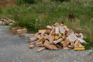 Tahta hurda yığını gün ışığında çakıl yolunun kenarında düzgünce istiflenmiş..