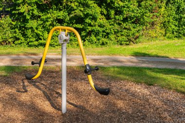 Parkta parlak sarı metal salıncak. Kapat..