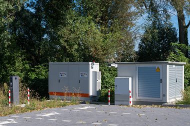 Çevresi yeşilliklerle çevrili, ağaçlarla çevrili bir alanın yanında, sakin bir günde, yerel hizmetler için hayati önem taşıyan altyapı sergileniyor..