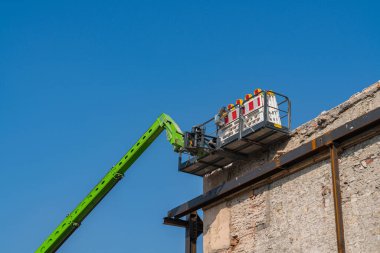 Bir binanın duvarına yakın bir asansör kabini yenileniyor mavi gökyüzünün arka planına karşı..