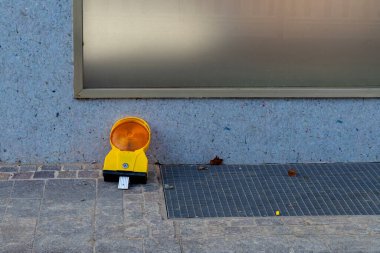 Parlak sarı bir inşaat ışığı modern bir binanın dış cephesinin yanında, potansiyel olarak tehlikeli bir bölgede görüş alanı sağlıyor..