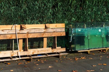 Yerdeki ahşap paletler ve büyük cam paneller renkli sonbahar yaprakları ve kentsel cadde boyunca yoğun bir yeşillik zeminiyle çevrili..