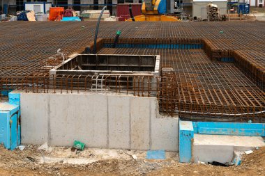İşçiler bir vakfın hazırlandığı bir inşaat sahasında meşguller. Güçlendirilmiş çelik çubuk ve beton formlar yapının temelini şekillendirir.