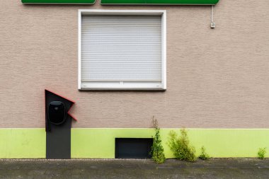 Elektrikli araçlar için bir şarj istasyonu binanın dış tarafında, yeşil bir duvar ve bitişik bir pencere ile zıt şık bir tasarım yer alıyor..