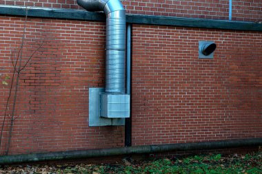 A metal ventilation duct extends from a brick wall, providing air circulation. Nearby, an additional exhaust vent is visible, indicating a focus on airflow management in this structure. clipart