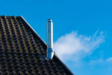 Metal bir baca, modern mimariyi gözler önüne seren eğimli bir çatıdan yükselir. Yumuşak bulutlar parlak mavi gökyüzünde sürükleniyor, yuvanın çağdaş tasarımını tamamlıyor..