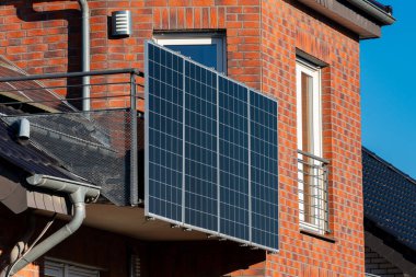 Güneş panelleri çağdaş bir tuğla dairenin balkonuna monte edilir. Bu kurulum doğrudan güneş ışığından yararlanır ve kentsel yaşam ortamlarında enerji verimliliğini arttırır..