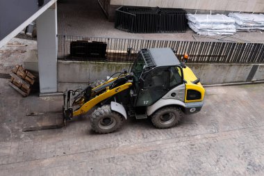 İnşaat alanındaki sarı forklift. Araç, malzeme taşımak ve taşımak için çatallarla donatılmıştır..