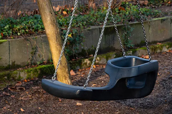 Boş bir salıncak seti, yemyeşil yeşilliklerle çevrili sakin bir parkta duruyor. Sakin bir öğleden sonra ışığı yumuşak gölgeler bırakır, huzur ve yansıma ortamı yaratır..