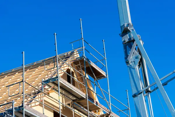 Ahşap yapıları destekleyen iskelenin yer aldığı inşaat halindeki bir binada çalışmalar devam ediyor. Açık mavi gökyüzü devam eden gelişme için çarpıcı bir zemin oluşturur.