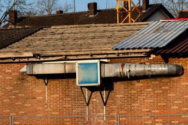 Büyük bir endüstriyel havalandırma sistemi inşaat faaliyetlerine yakın terk edilmiş bir fabrikada tuğla bir binadan uzanıyor..